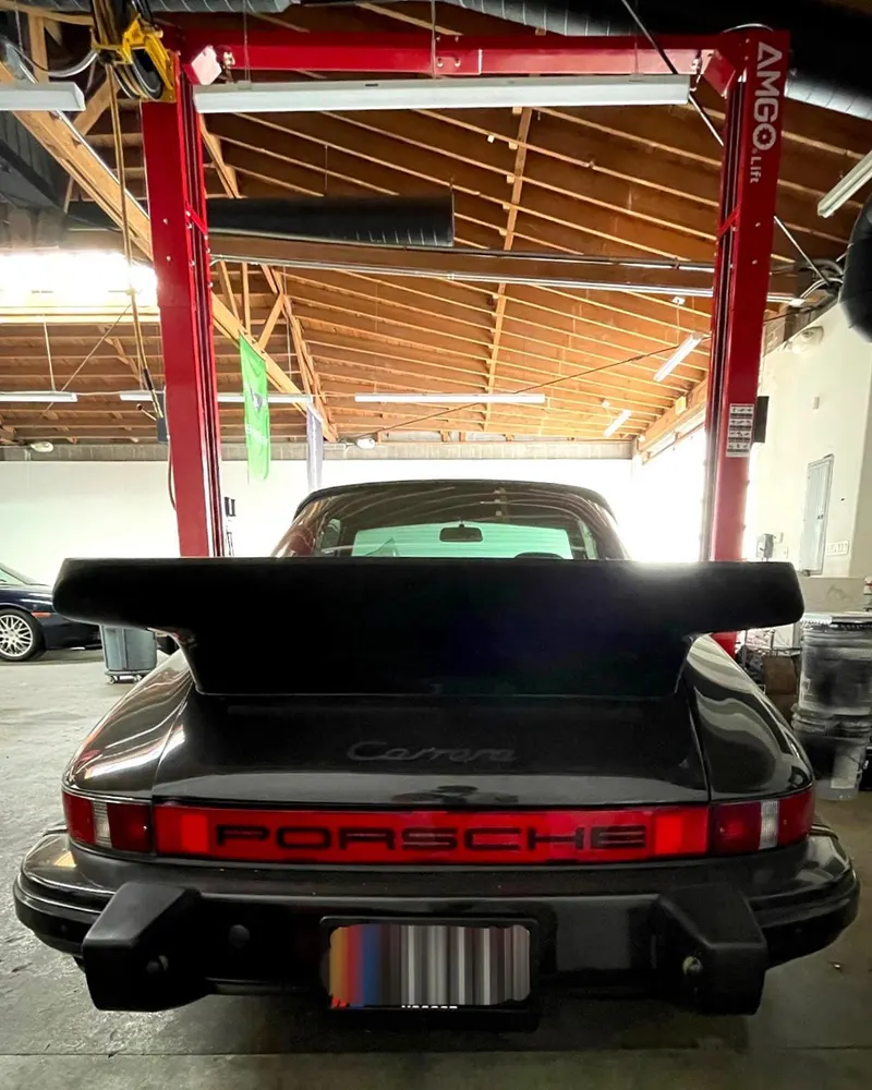 Rear of an air-cooled Porsche 911 with a whale-tail spoiler in the shop