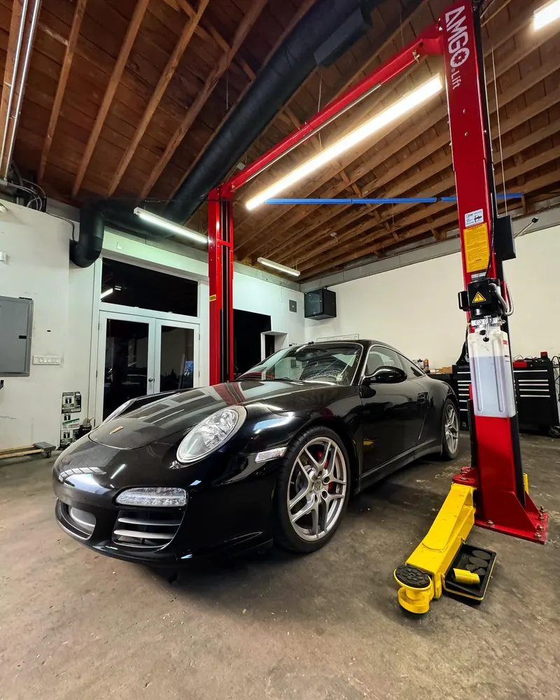 Black Porsche 911 parked beside a two-post lift