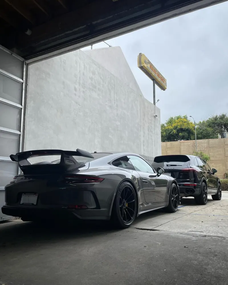 Grey Porsche 911 GT3 and a Porsche Macan parked outside the shop