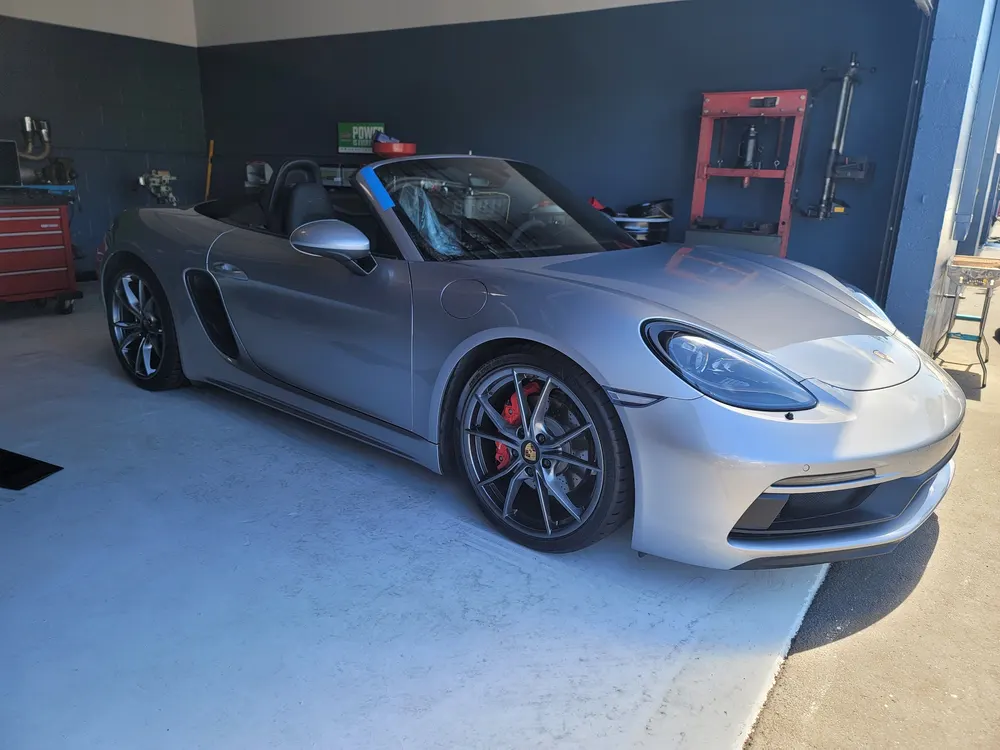 Silver Porsche 718 Boxster parked in a service bay