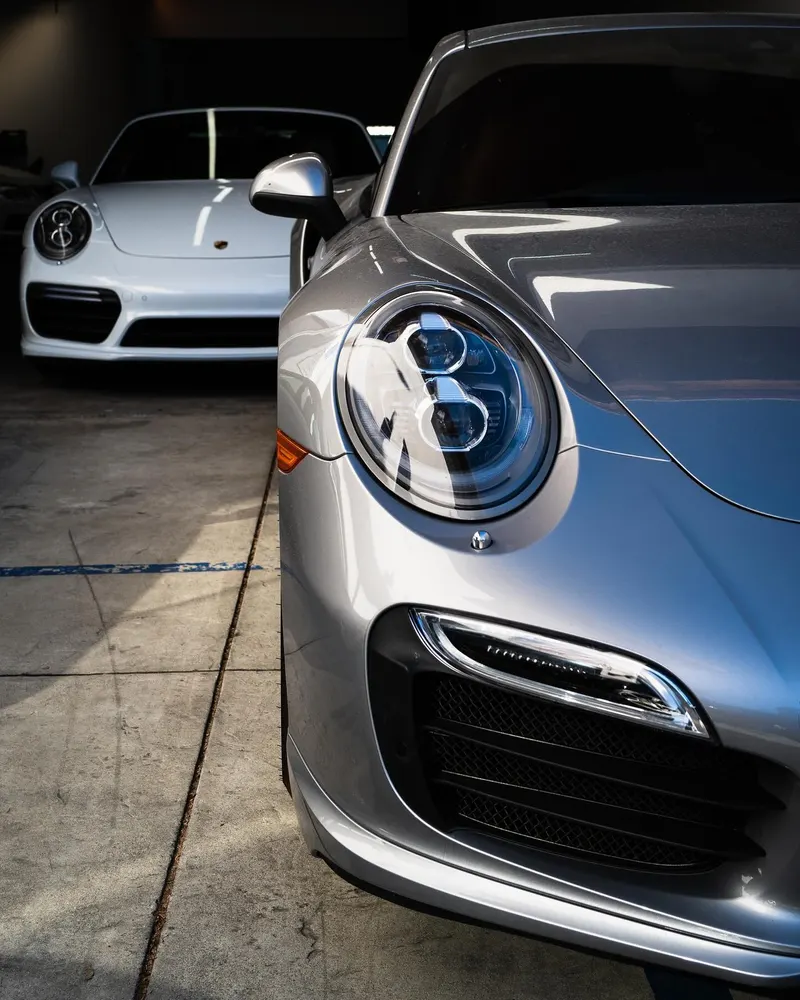Front of a silver Porsche 911 with a white 911 behind it